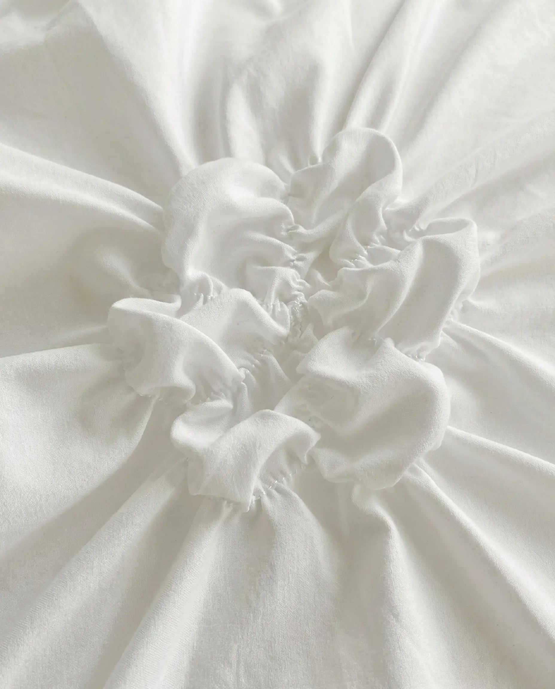 Detailed close up of ruched fabric texture on white duvet cover with soft gathered stitching
