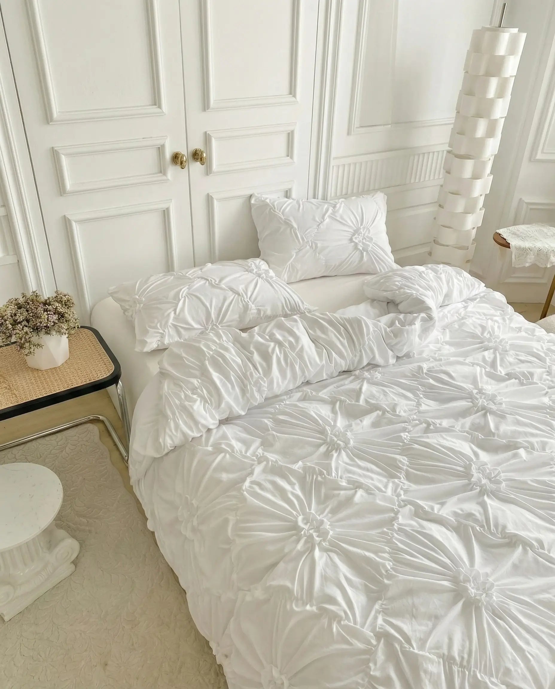 Textured white duvet cover with ruched detailing styled on bed in minimal neutral bedroom