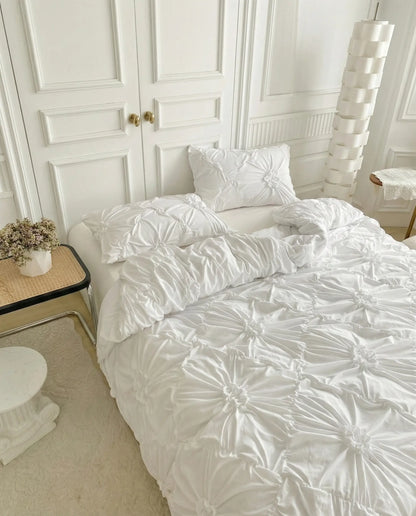 Textured white duvet cover with ruched detailing styled on bed in minimal neutral bedroom