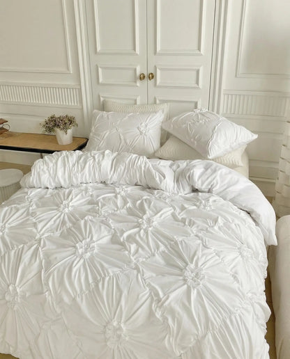 White ruched duvet cover set with matching pillow shams styled in airy contemporary bedroom