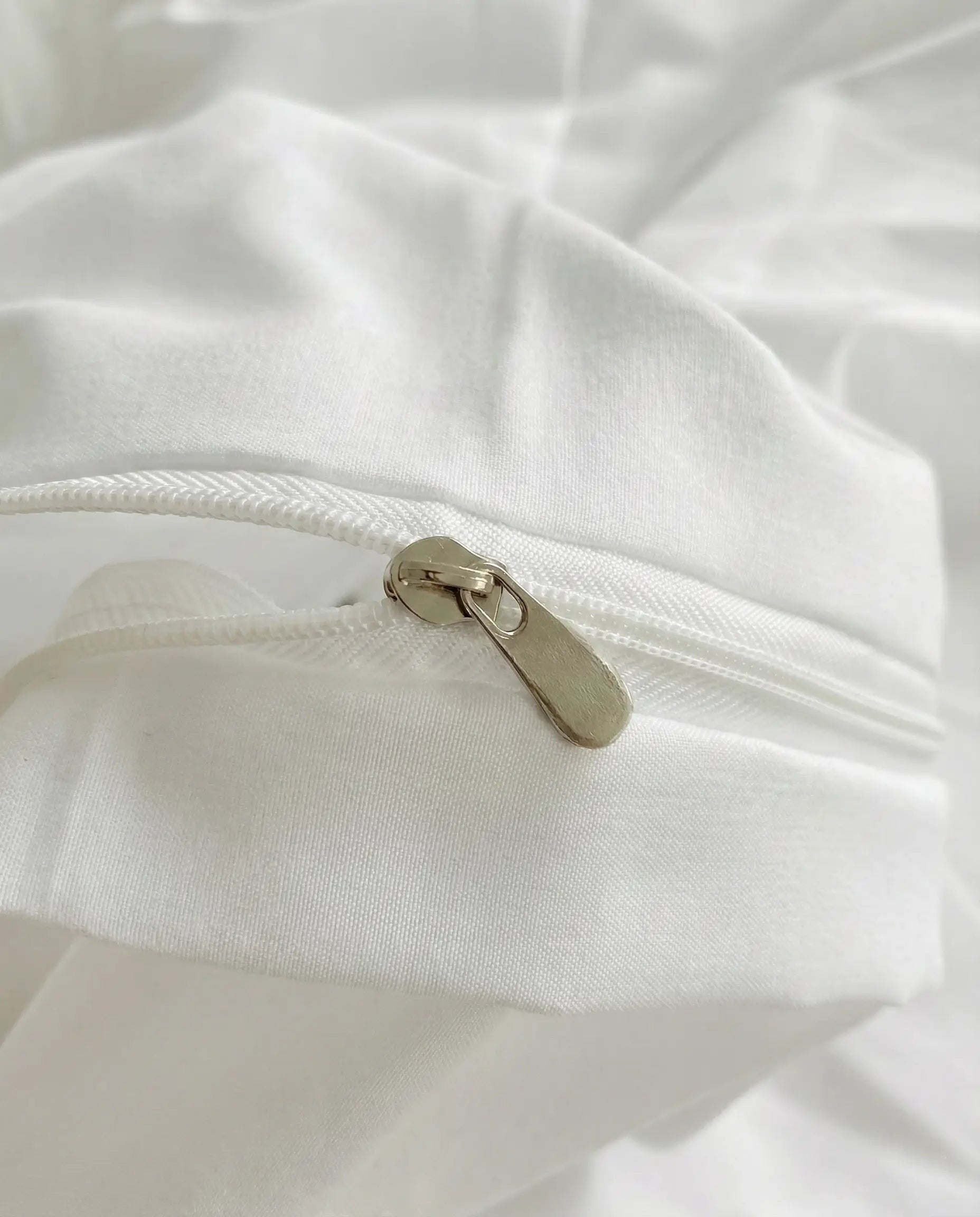 Close up of hidden zipper closure on white ruched duvet cover with smooth fabric finish