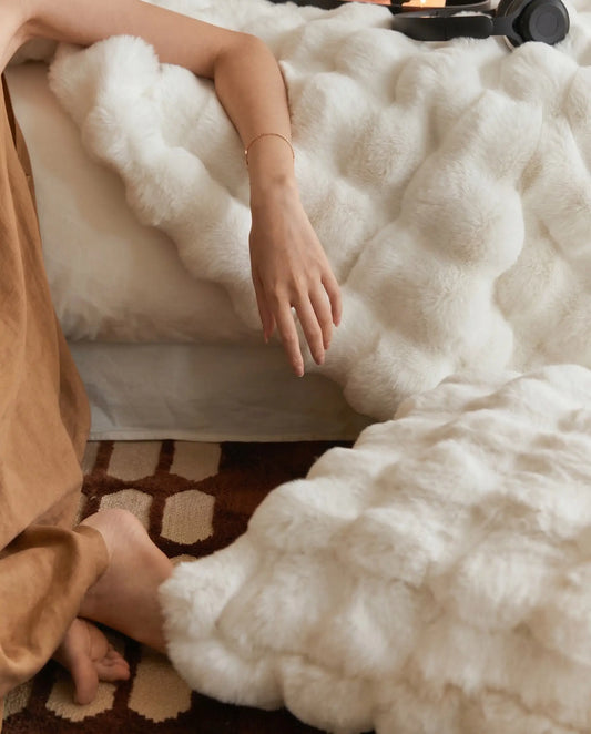 Hand lifting DORMÉ Studio Marshmallow Ultra Plush Blanket revealing cloud like plush texture and luxurious softness. White