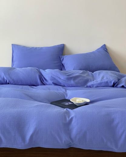 Ultramarine crinkle muslin duvet cover and pillowcases on an unmade bed