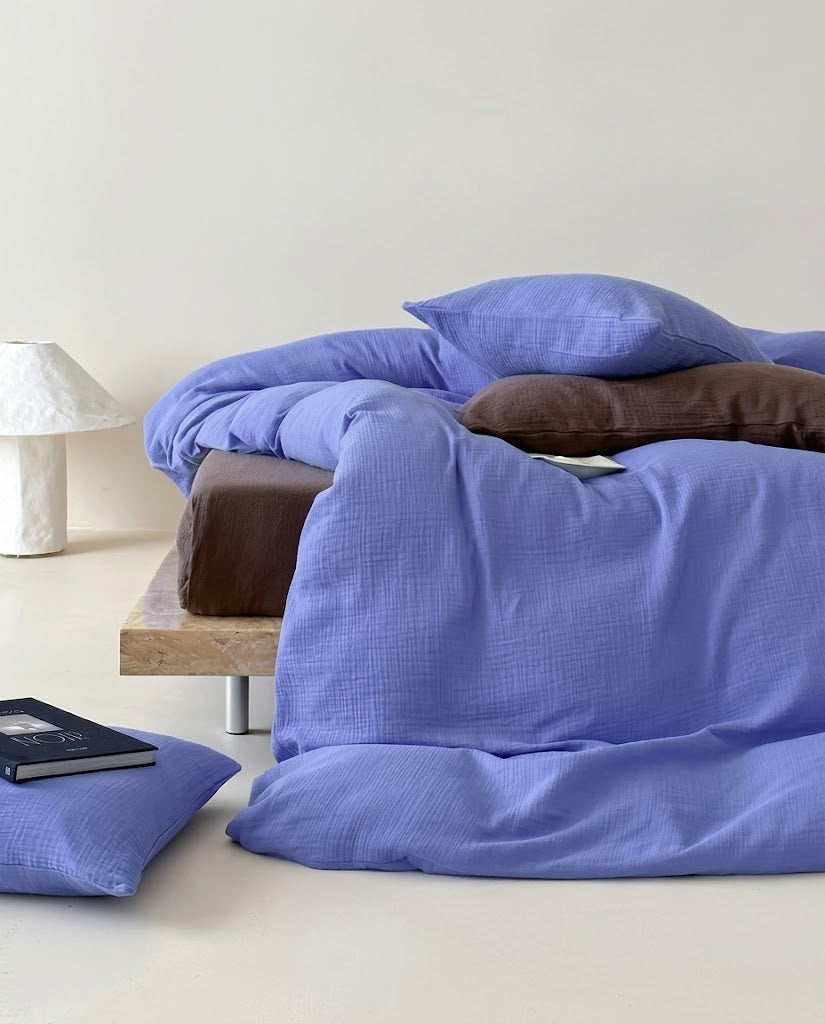 Ultramarine cotton gauze duvet cover draped from a low bed to the floor