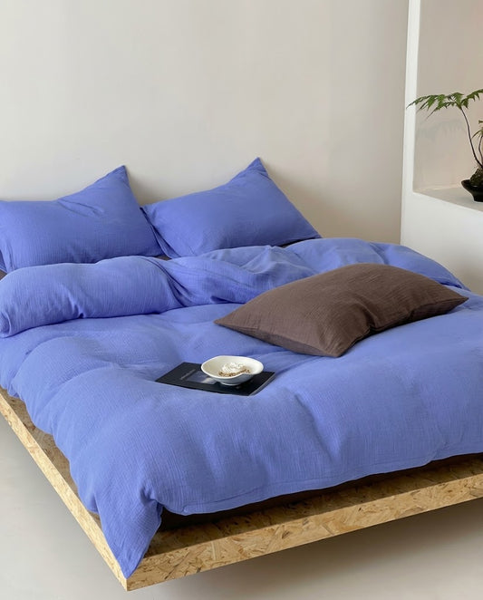 Ultramarine muslin duvet cover with a brown accent pillow on a platform bed