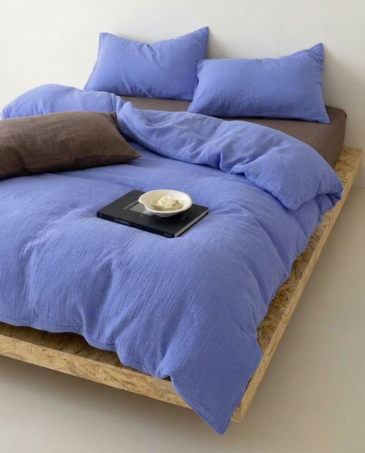 Ultramarine muslin duvet cover set on a wooden platform bed with a brown fitted sheet