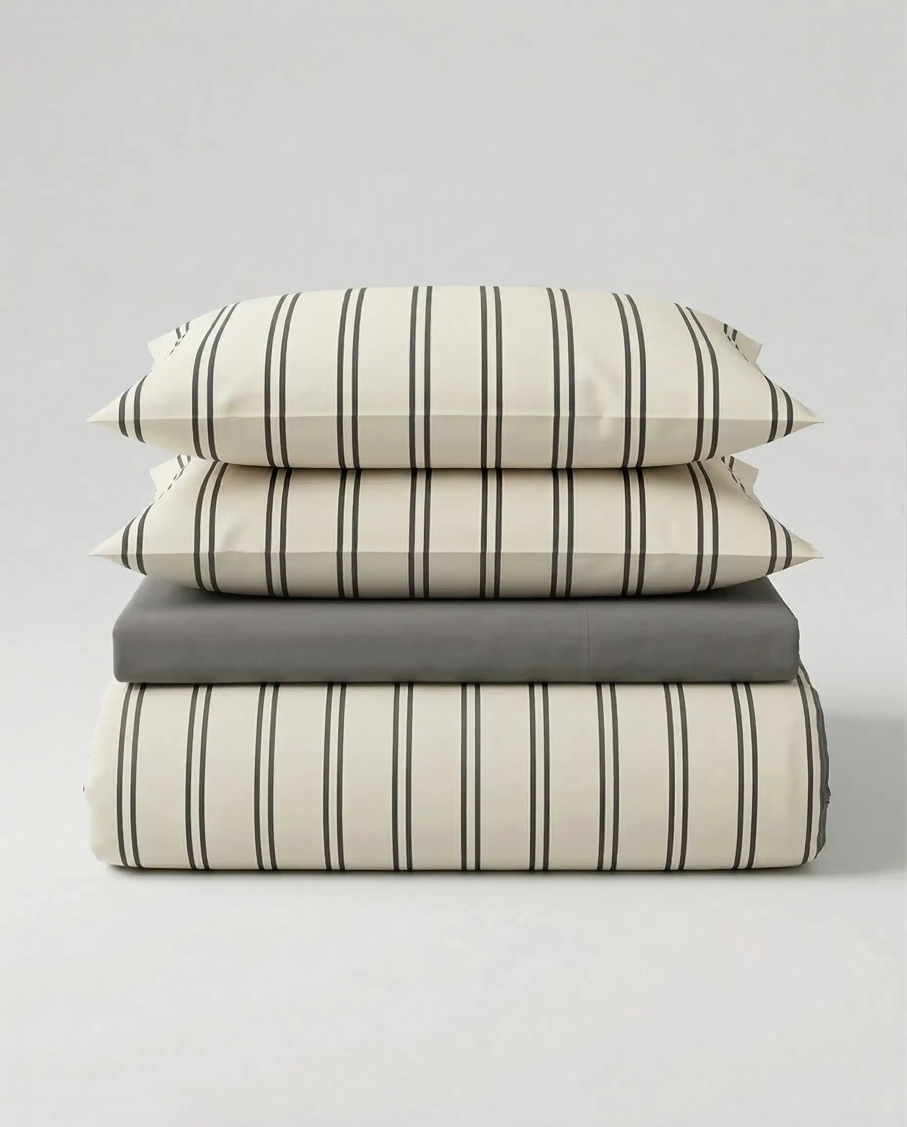 Stacked view of the DORMÉ Studio Urban Stripe Duvet Cover Set featuring soft ivory cotton bedding with thin charcoal pinstripes and matching pillow shams. This modern striped duvet cover set offers a clean, minimalist aesthetic and timeless neutral design that elevates any bedroom with hotel-inspired comfort and refined style.