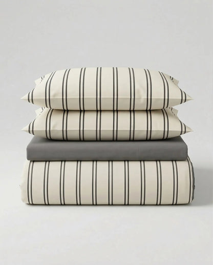 Stacked view of the DORMÉ Studio Urban Stripe Duvet Cover Set featuring soft ivory cotton bedding with thin charcoal pinstripes and matching pillow shams. This modern striped duvet cover set offers a clean, minimalist aesthetic and timeless neutral design that elevates any bedroom with hotel-inspired comfort and refined style.