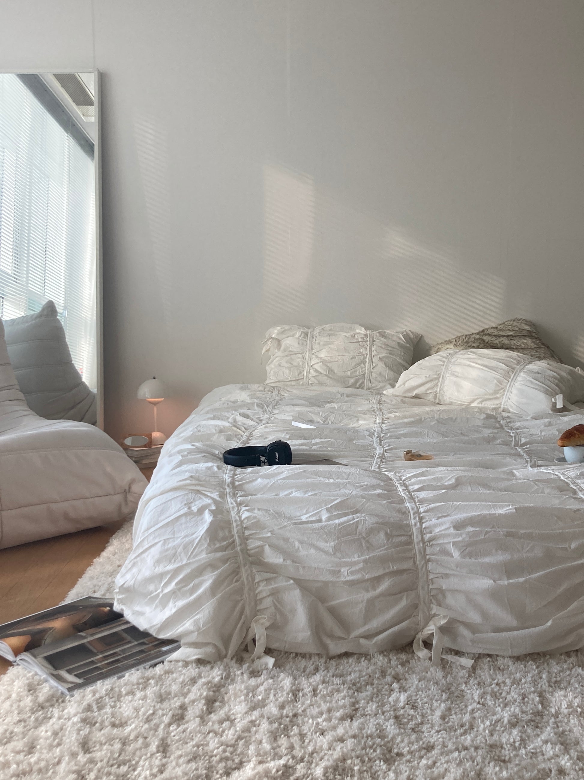 Classic White Ruched Duvet Cover Set on a floor-level platform bed in a minimalist bedroom with soft morning sunlight and a shaggy white rug